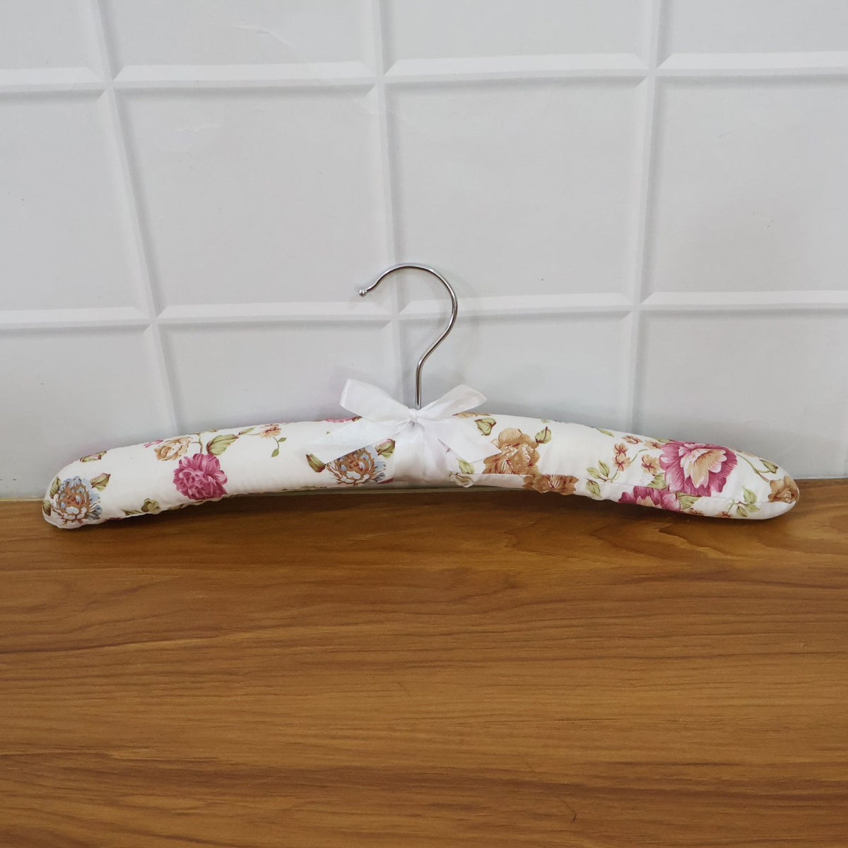 Close-up of floral bow detail on premium satin-padded clothes hanger